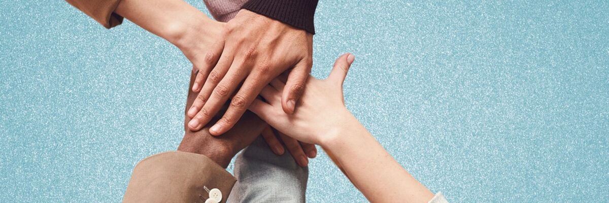 Symbolic image: several people's hands resting flat on top of one another