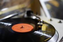Close-up: cartridge on a spinning vinyl record with an orange label